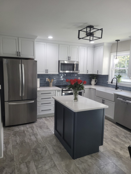Charleston SC kitchen renovation — white shaker cabinets with matte black hardware, navy blue island with quartz countertop, blue subway tile backsplash, farmhouse sink, and black cage semi-flush ceiling light by KDC Interiors