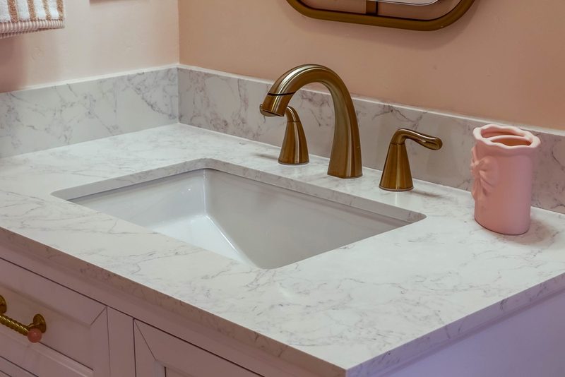 Brass faucet on the quartz vanity countertop, by KDC Interiors