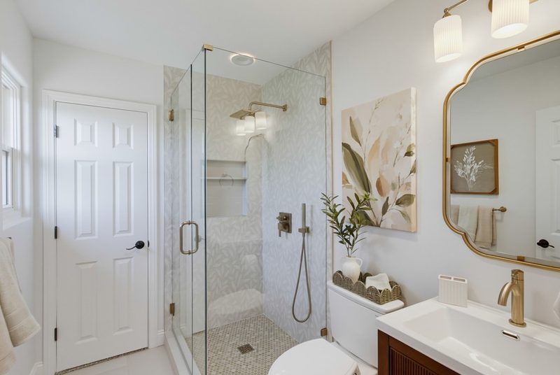 After: a frameless glass shower, reeded walnut storage vanity, gold mirror, and botanical art, by KDC Interiors