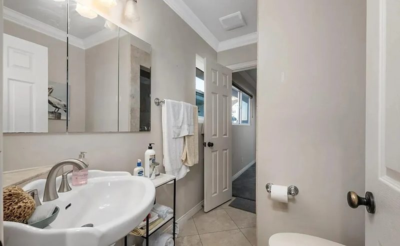 Before: the guest bath with a pedestal sink, an enclosed shower, and no storage