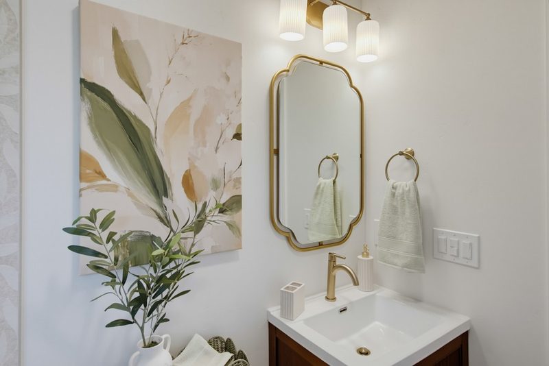 Walnut vanity with botanical art and a gold mirror, by KDC Interiors