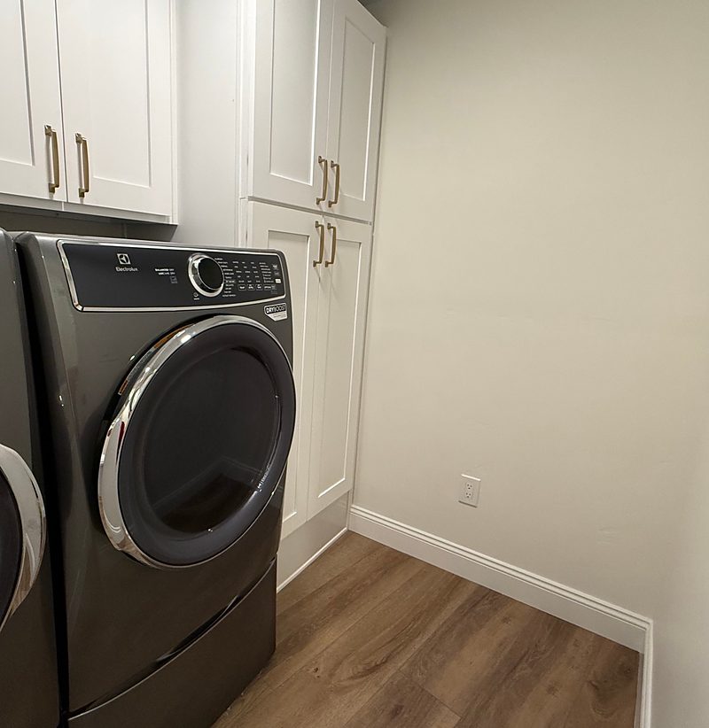 After: the new laundry room with white shaker cabinets and pool towel storage, by KDC Interiors