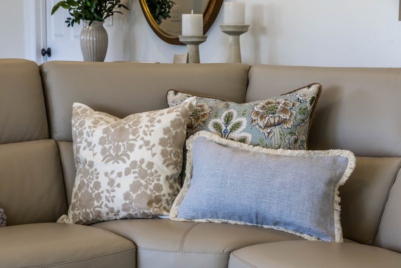 Layered blue and taupe pillows on the leather sectional, by KDC Interiors