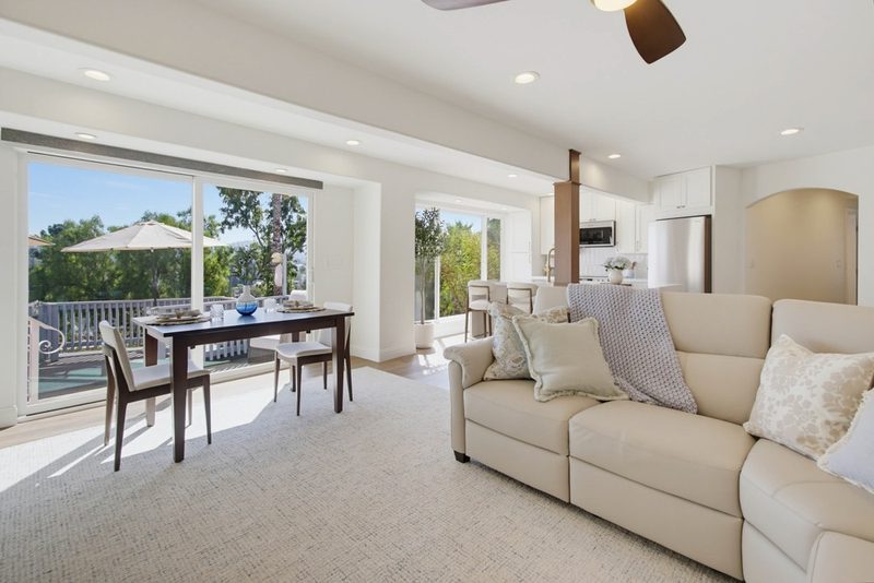 After: defined dining and living zones with water-resistant flooring and a sectional oriented to the outdoor views, by KDC Interiors
