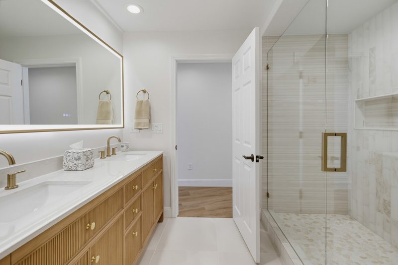 After: a dual reeded oak vanity with a backlit mirror and a frameless walk-in shower, by KDC Interiors