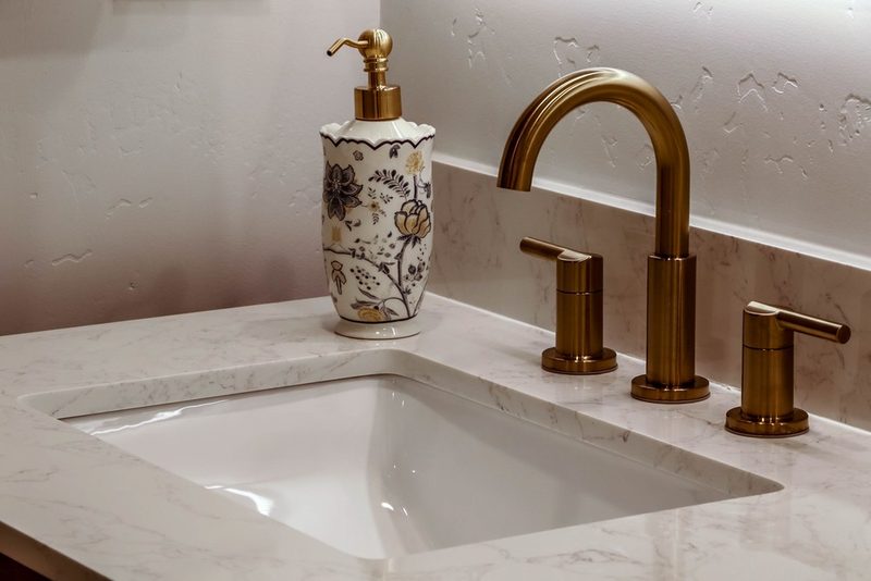 Brass widespread faucet on the quartz vanity countertop, by KDC Interiors