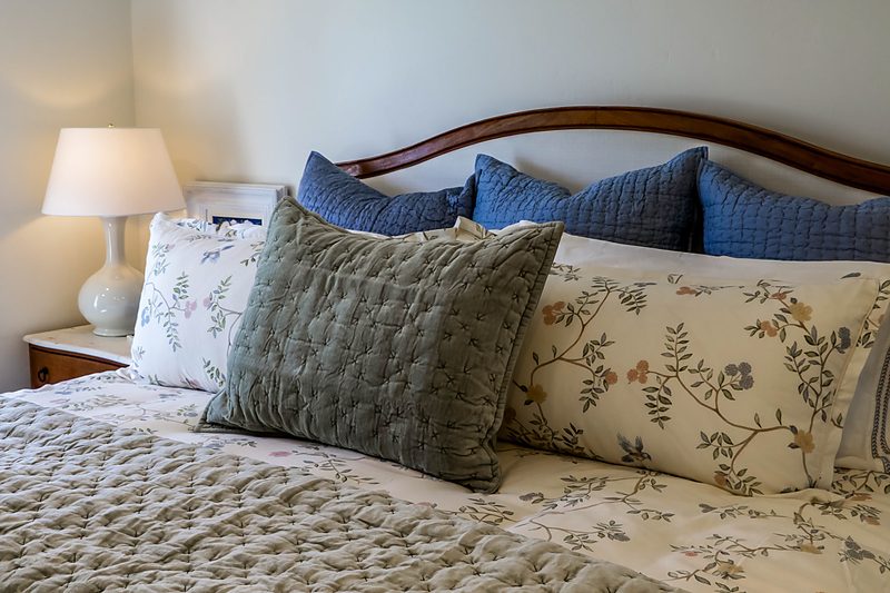 Layered blue and sage pillows on the king bed, by KDC Interiors