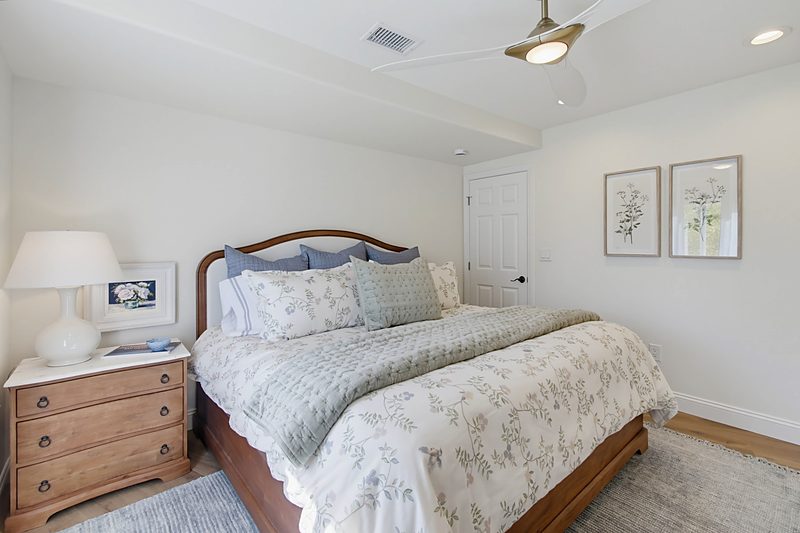 King bed with floral bedding, botanical prints, and wood nightstands in a soft neutral palette, by KDC Interiors
