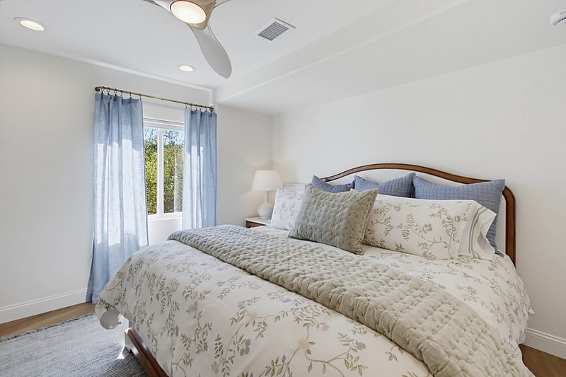 Bed beside the window with light-filtering curtains, by KDC Interiors